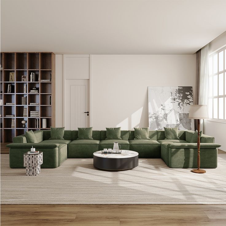 a living room filled with green couches next to a white table and bookshelves