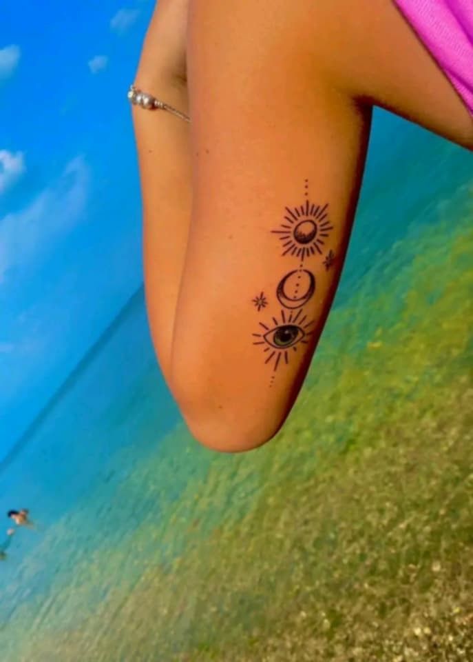 a woman's leg with the sun and moon tattoo on it, next to water