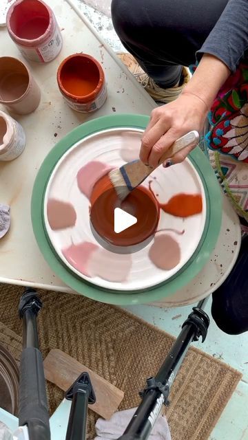 a person painting on a plate with paint