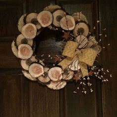 a wreath made out of logs and dried flowers on the front door to a home