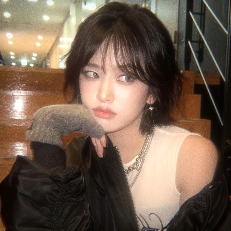 a woman in white shirt and black jacket sitting on stairs with hand over her face