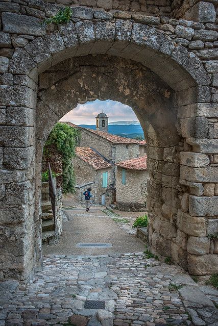 an old stone building with stairs leading up to the door and through it is a cobblestone street