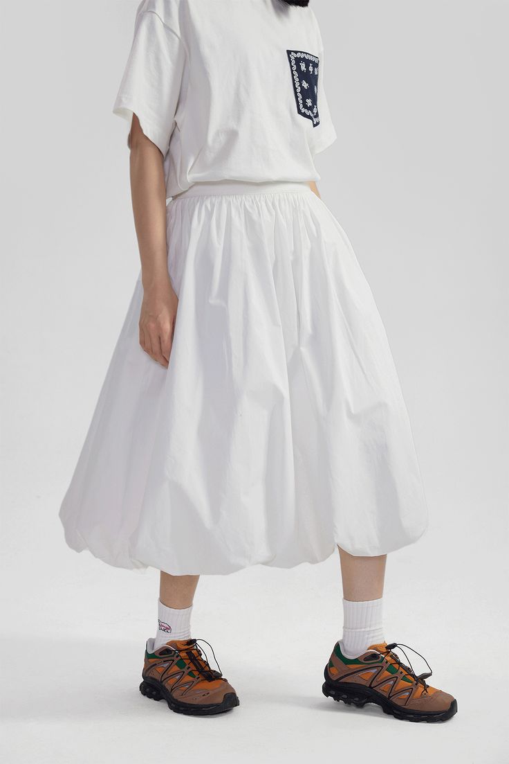 Elevate your wardrobe with this High-Waisted Pleated Slip Midi Skirt – a timeless piece blending a touch of retro charm with modern sophistication. Meticulously crafted from 100% cotton, this skirt features an array of finely tailored pleats that create a voluminous silhouette, enhancing its graceful movement. The solid color and subtle texture offer a versatile base for an array of styling options. A natural waistline and A-line cut promote a flattering fit, while practical side pockets bring a Voluminous Skirt Outfit, Flared Skirt Bottoms With Pleated Hem For Daywear, Chic Relaxed Fit Full Skirt Bottoms, Elegant Long Skirt With Relaxed Fit, Gathered Full Skirt For Daywear, Classic Cotton Bottoms With Voluminous Skirt, High Waist Cotton Gathered Skirt, Daywear Bottoms With Pleated Waist And Flared Skirt, High Waist Gathered Cotton Skirt