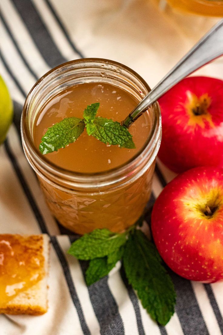 an apple cider and two pieces of bread on a striped tablecloth with apples in the background