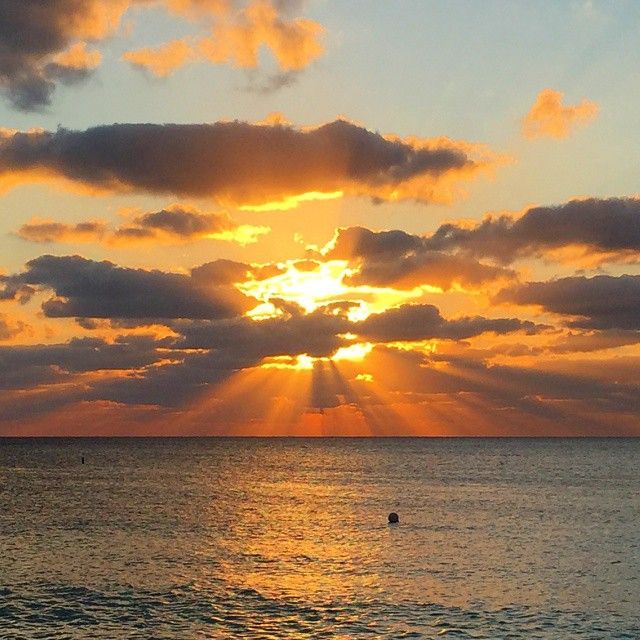 the sun is setting over the ocean with clouds in the sky and water below it