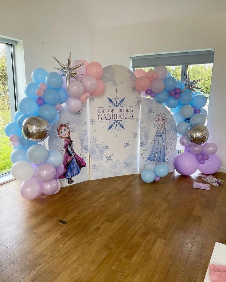 balloons are on the floor in front of an arch with frozen princesses and snowflakes