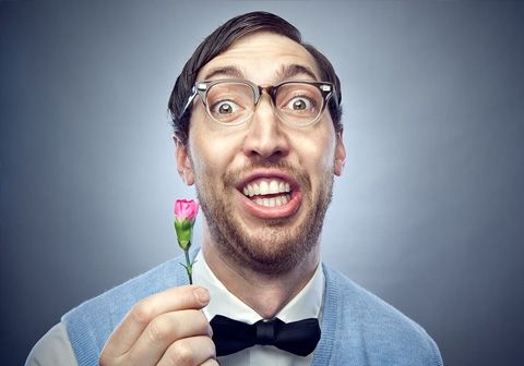 a man holding a pink rose up to his face and looking at the camera with an amazed look on his face