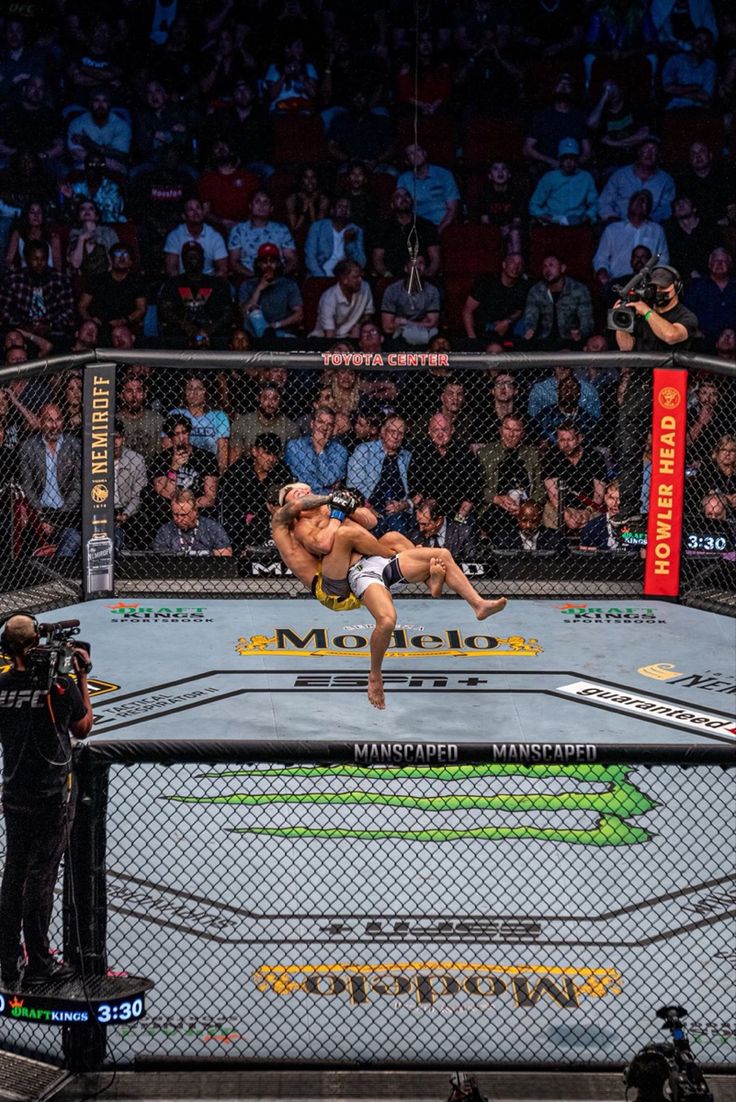 a man is in the middle of a wrestling match, with spectators watching from the sidelines