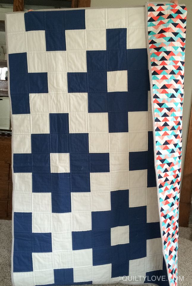 a large blue and white quilt sitting next to a tall piece of cloth on the floor