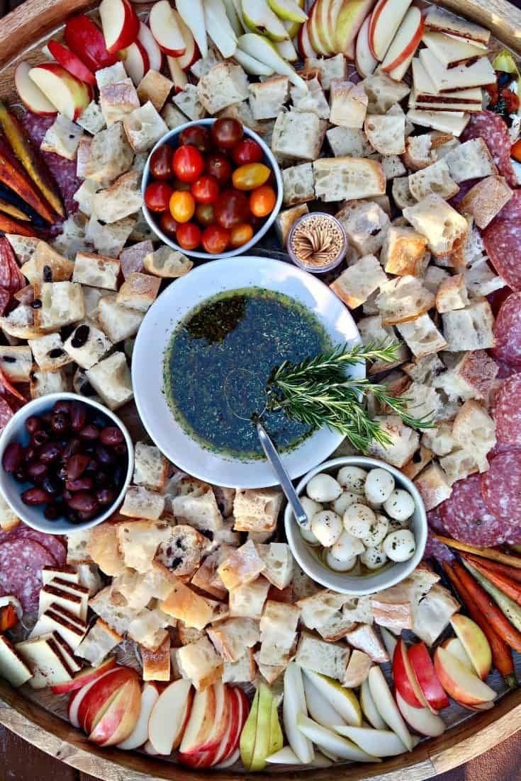 a platter filled with meats, vegetables and fruit