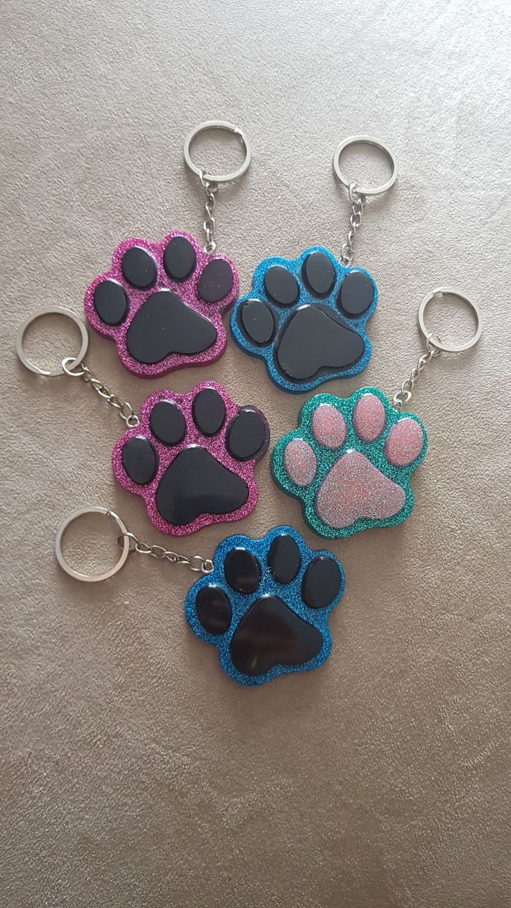 four key chains with paw prints on them sitting on a table next to each other