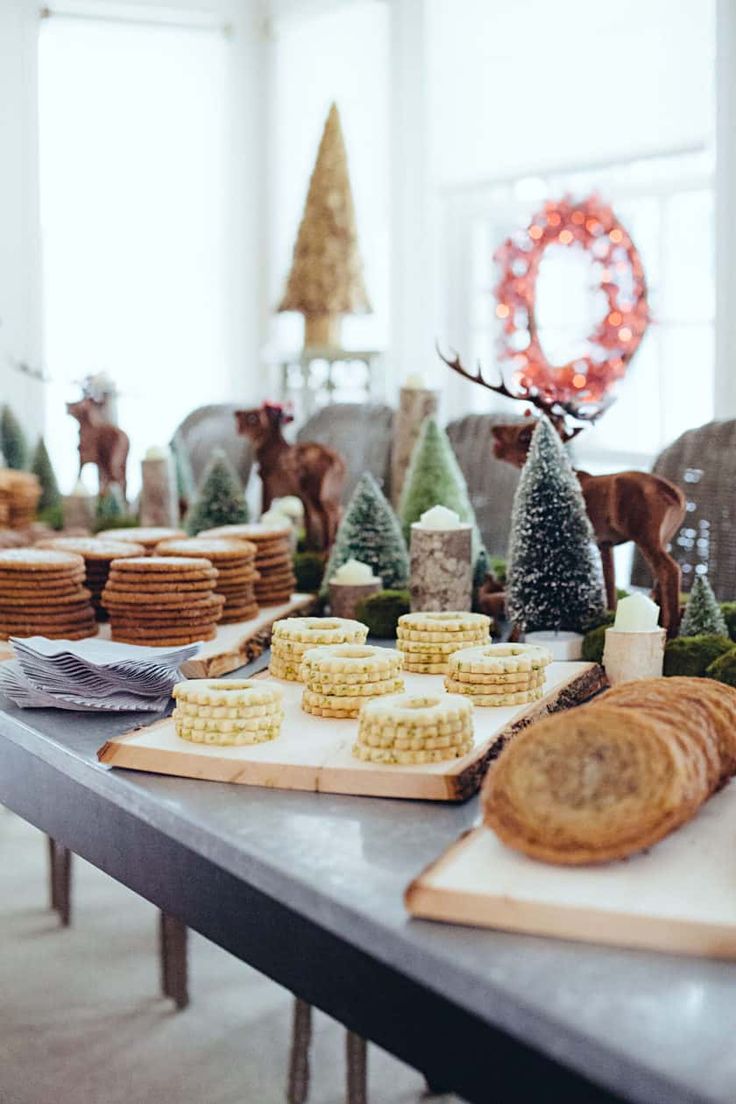 a table topped with cookies and other desserts next to a christmas tree in the background