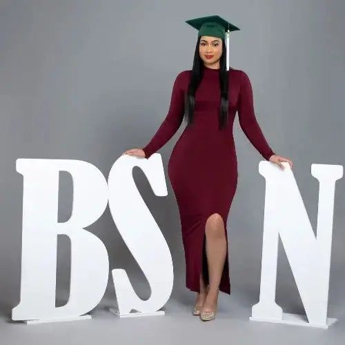 a woman in a graduation cap and gown standing next to the letters bsn with her hands on her hips