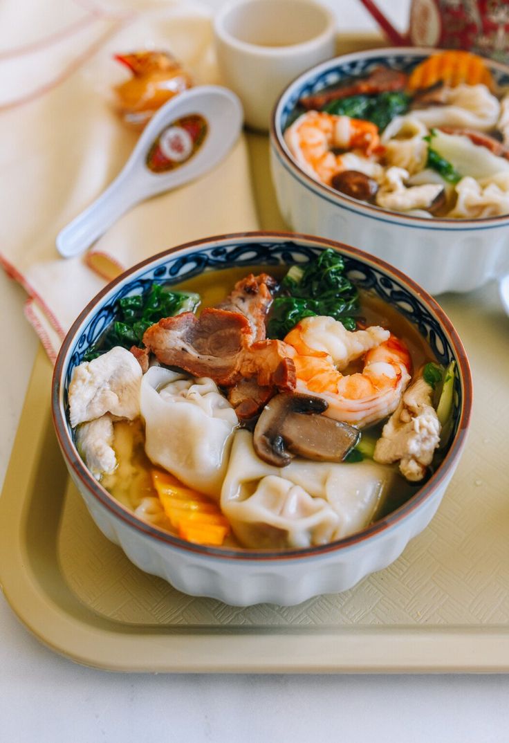 two bowls filled with food on top of a tray next to spoons and utensils