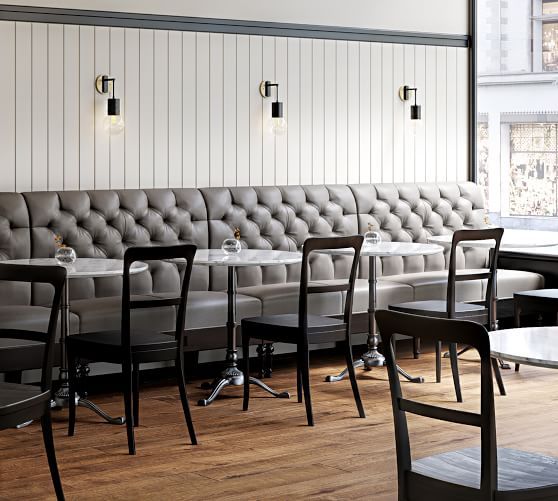 an empty restaurant with tables and chairs in front of a white paneled wall,