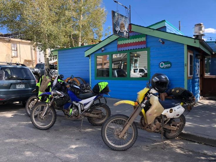 three motorcycles parked in front of a blue building