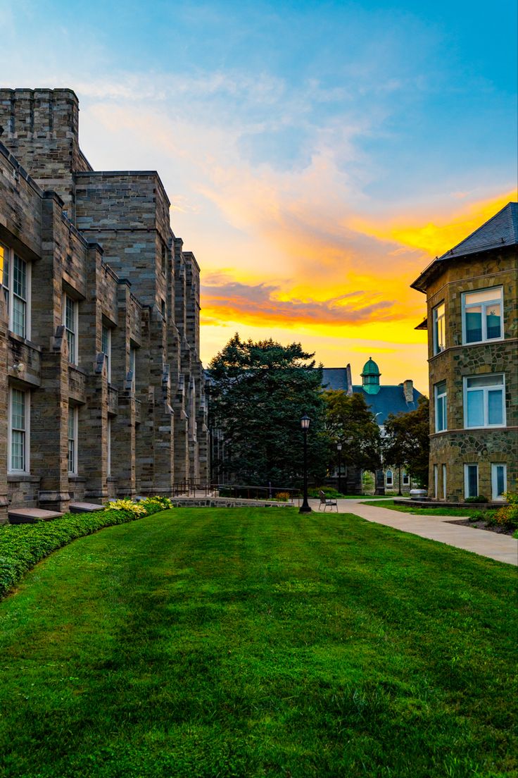 the sun is setting over an old brick building with green grass in front of it