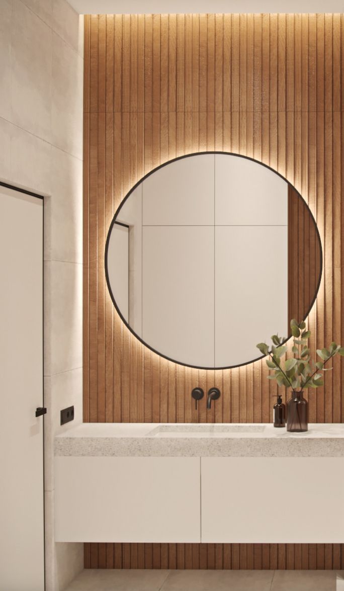 a bathroom with a large round mirror on the wall and wooden paneling behind it