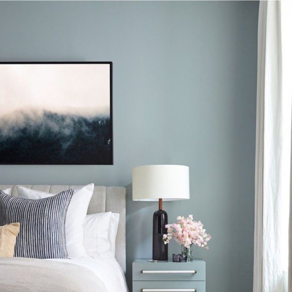 a white bed sitting next to a window in a bedroom under a painting on the wall