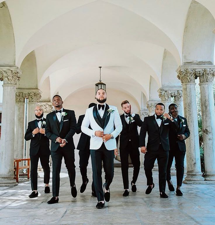 a group of men in tuxedos standing next to each other under an archway