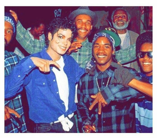 a group of young men standing next to each other in front of a crowd with one pointing at the camera