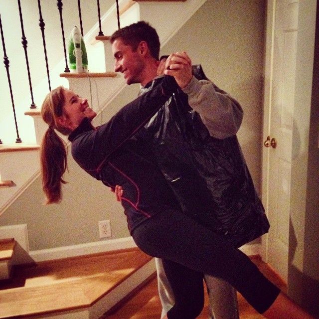 a man carrying a woman in his arms while standing on the floor next to stairs