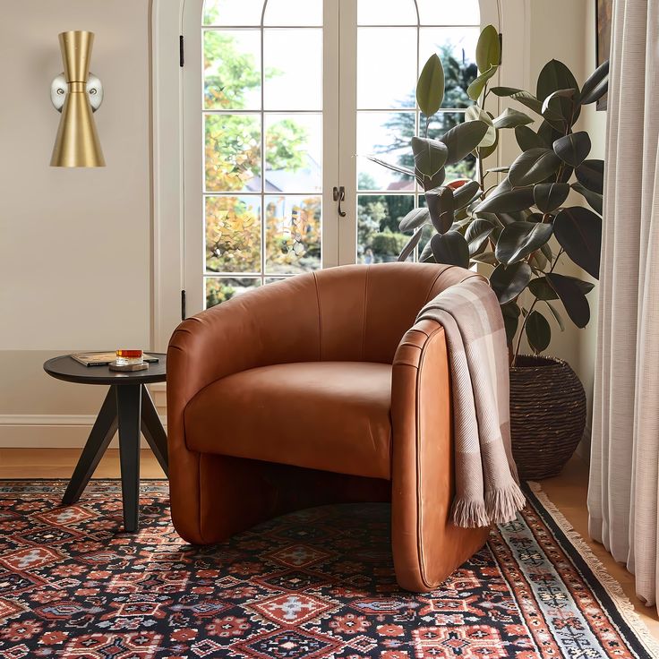 a brown leather chair sitting on top of a rug in front of a window next to a potted plant