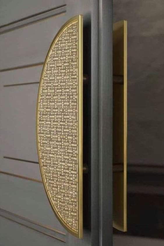 a close up of a metal door handle on a gray and gold colored door frame