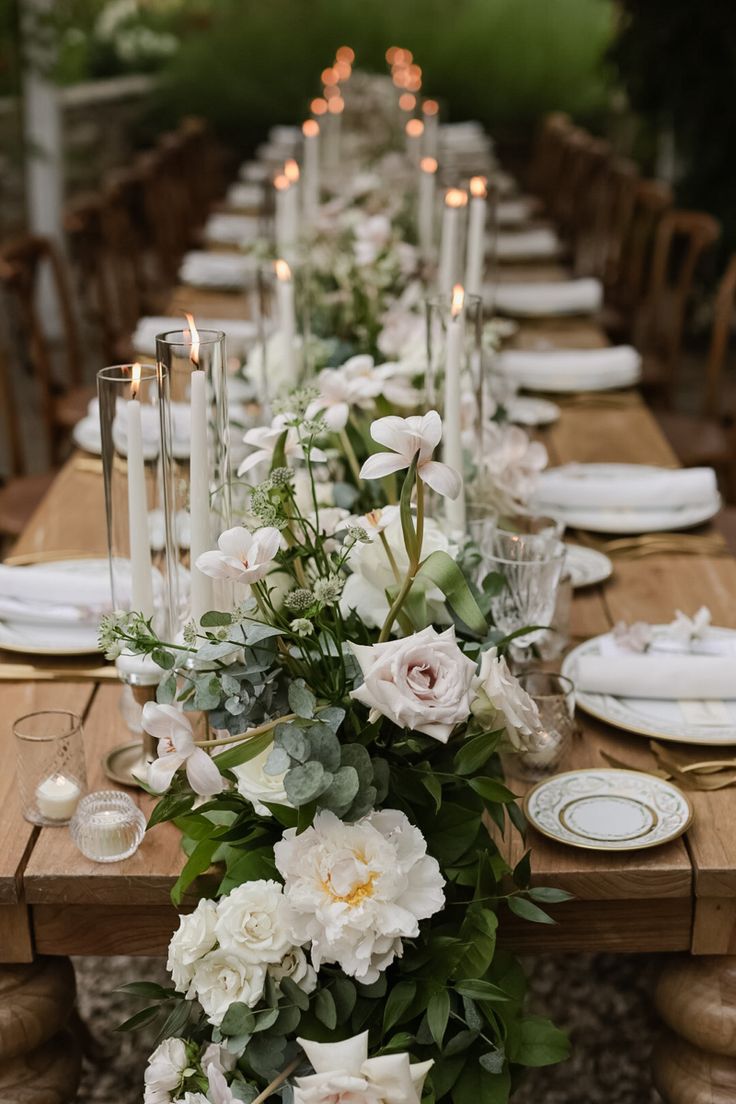 a long table with white flowers and candles is set up for an elegant dinner party