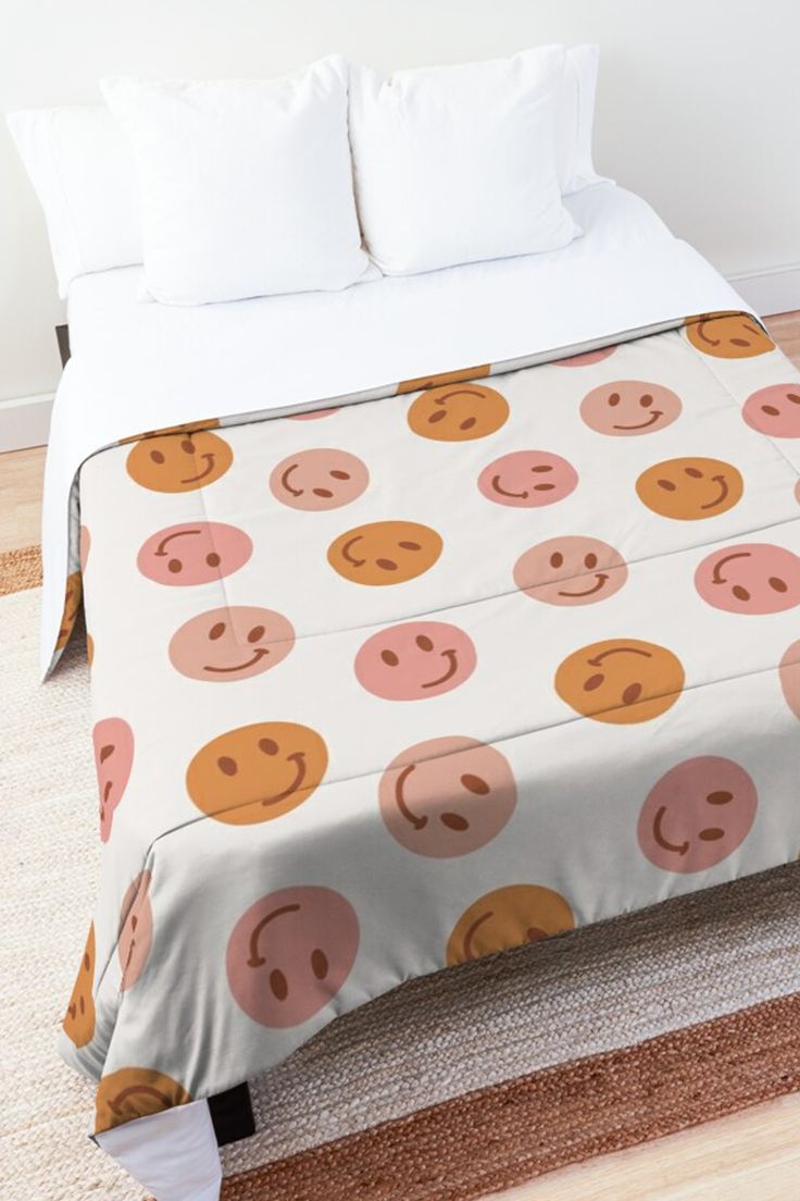 a bed covered in a white sheet with pink and orange smiley faces on it