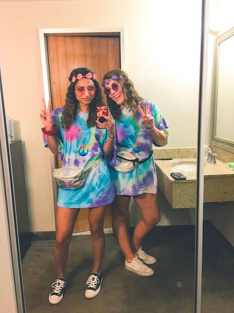 two women in tie - dye outfits are standing in front of a mirror and making the peace sign with their hands