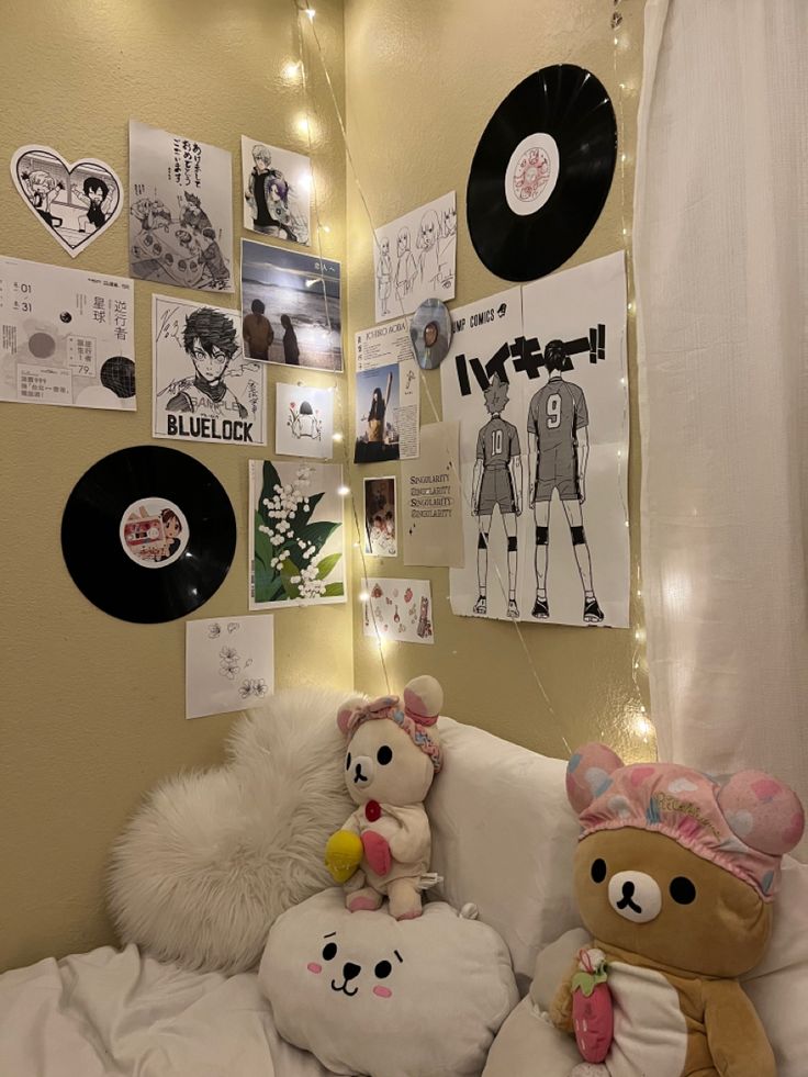 two teddy bears sitting on a couch in front of a wall with records and pictures