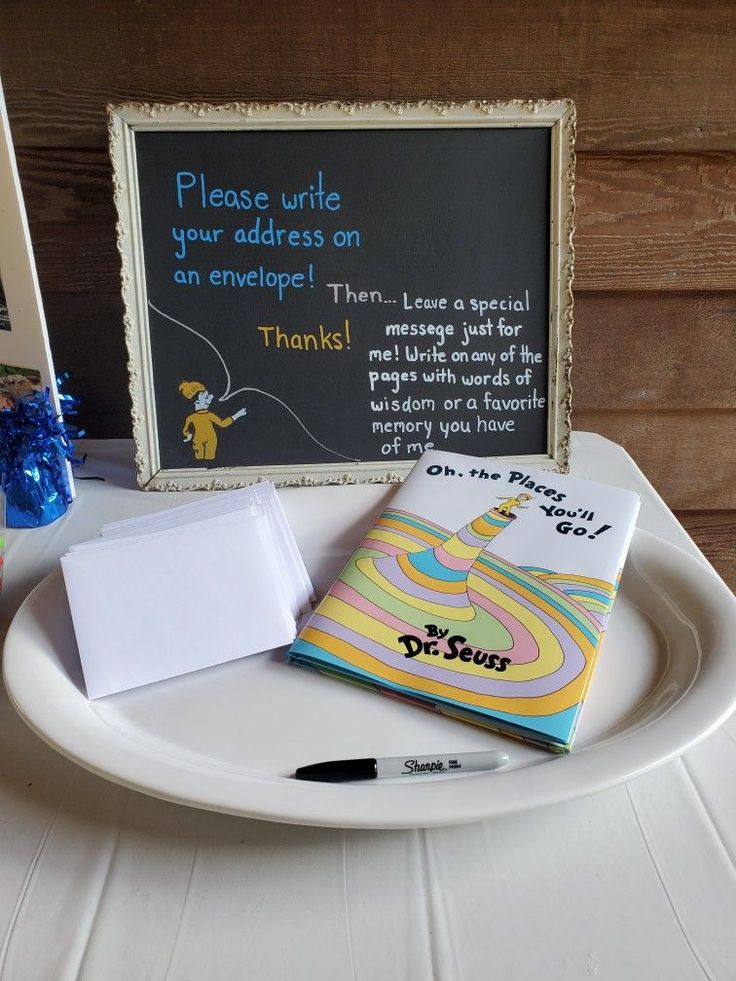 a white plate topped with books next to a chalkboard sign and blue vases