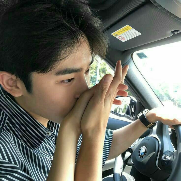 a man sitting in the driver's seat of a car holding his hands to his face