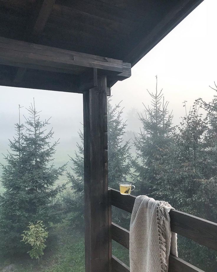 a towel hanging on the side of a wooden porch with trees in the back ground