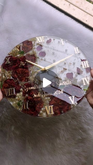 a person holding up a clock with flowers on it