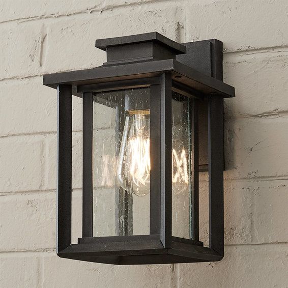 an outdoor light on the side of a brick wall with two clear glass bulbs hanging from it