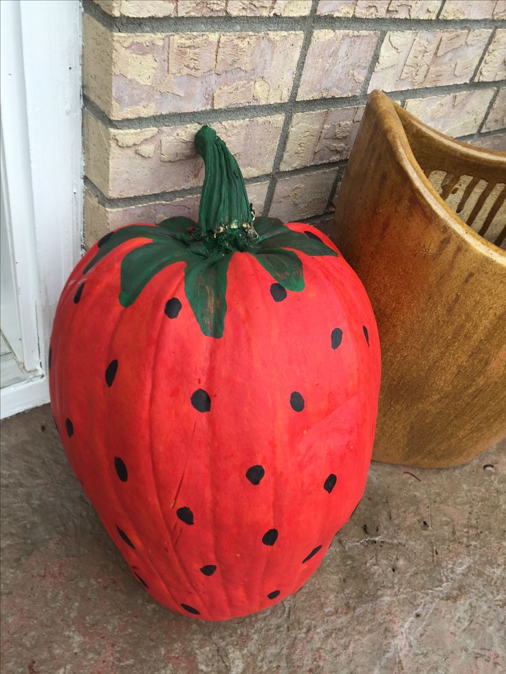 a pumpkin sitting on the ground next to a potted plant