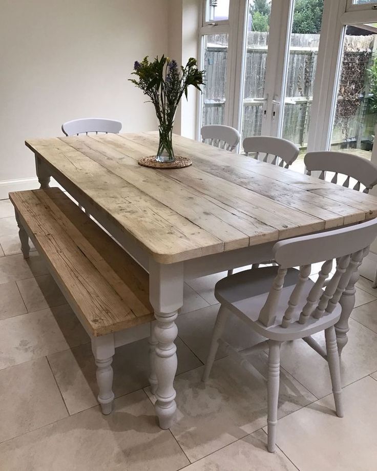 a wooden table with white chairs and a bench in front of it on tile flooring