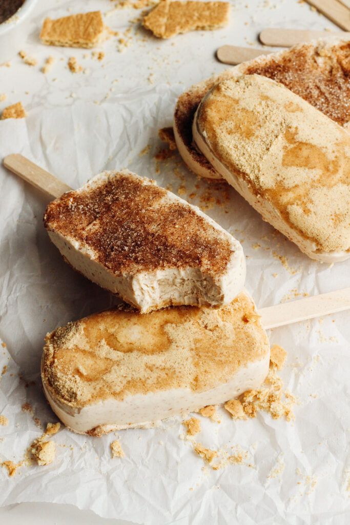 three ice cream sandwiches sitting on top of a white paper covered table next to wooden spoons