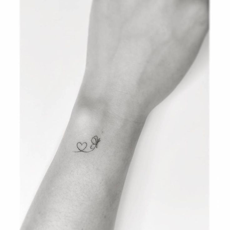 a small tattoo on the wrist of a woman's left arm, with two hearts and a butterfly