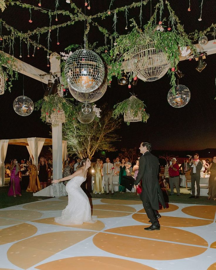 a bride and groom dancing under disco ball chandeliers