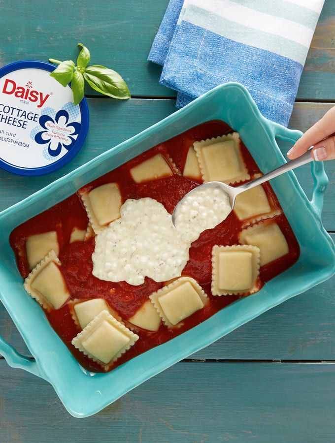 a blue tray filled with ravioli and cheese on top of a table next to a napkin