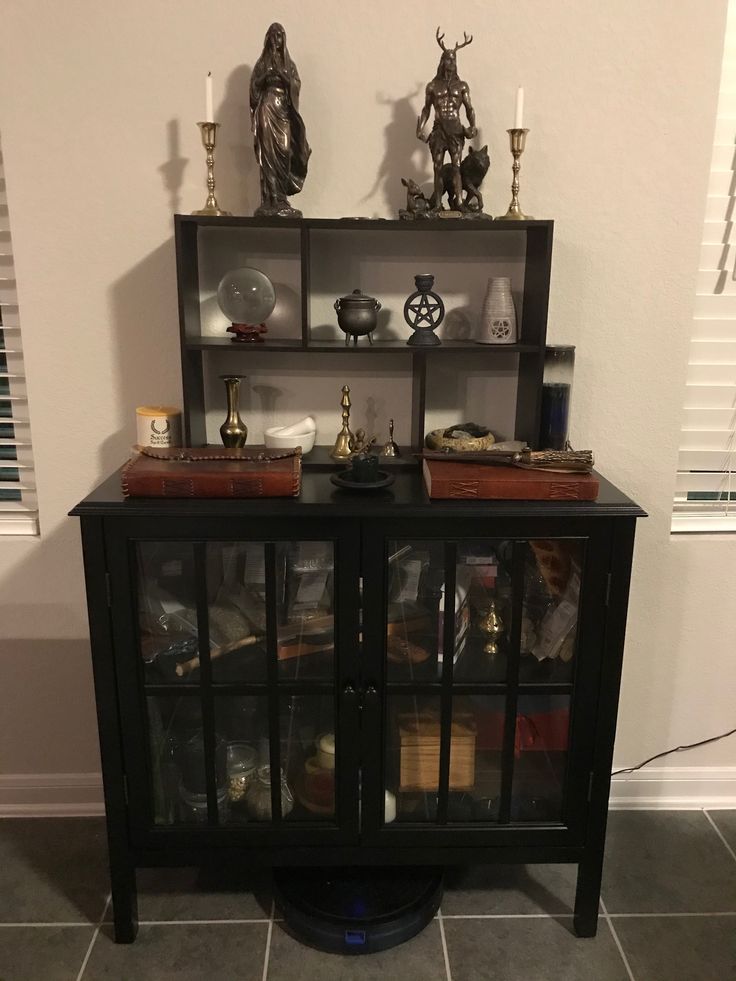 a black cabinet with glass doors and shelves filled with various items on top of it