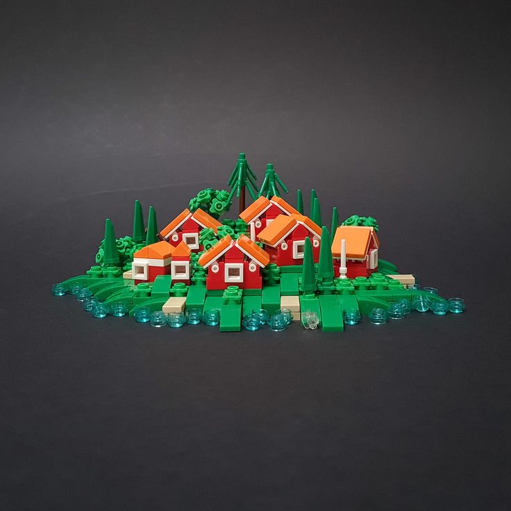 a group of lego houses sitting on top of a green field