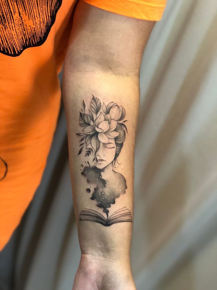 a woman's arm with a book and flowers tattooed on the left inner arm