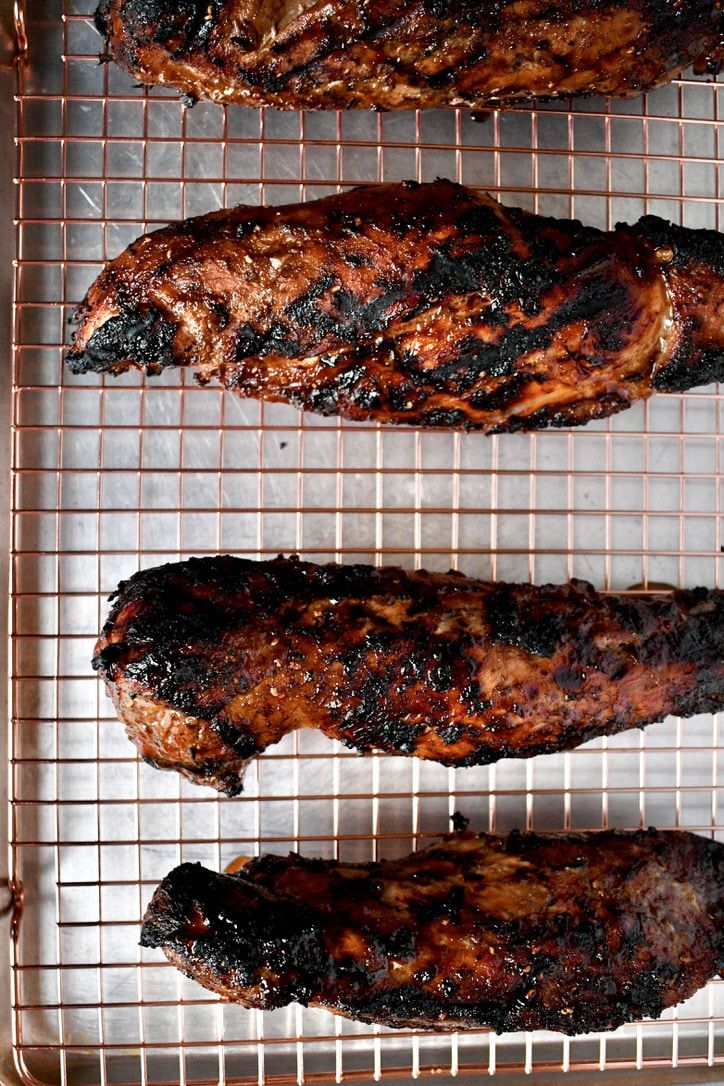 three grilled meats sitting on top of a metal rack