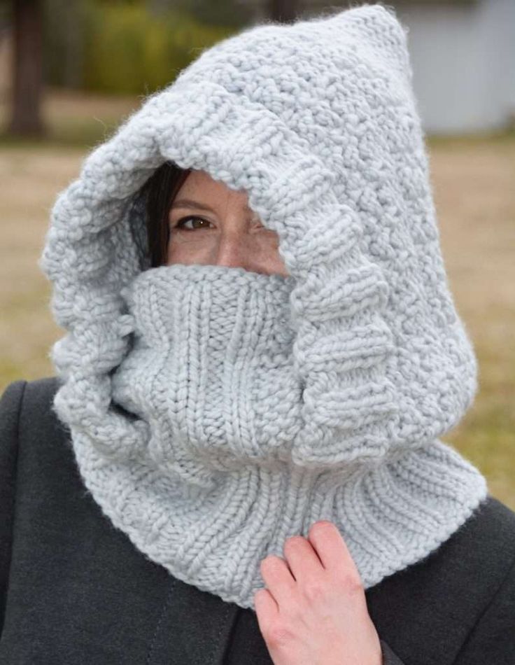 a woman wearing a knitted hood and covering her face with a scarf around her neck