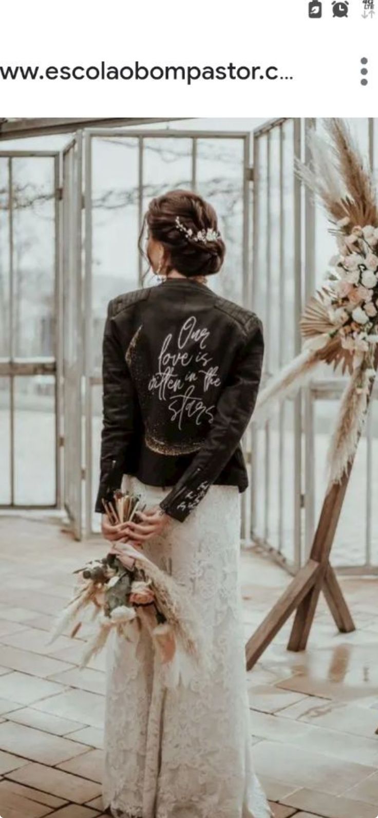 a woman standing in front of a glass wall wearing a black jacket and white dress