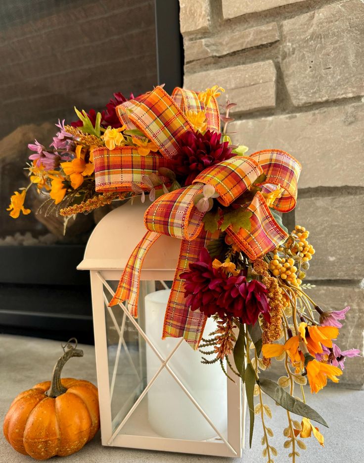 a lantern decorated with fall flowers and a bow